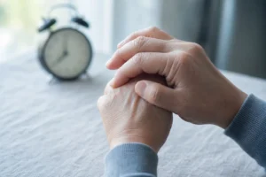 Dłonie rozmasowujące zesztywniałe palce dłoni o poranku, w chłodnym świetle