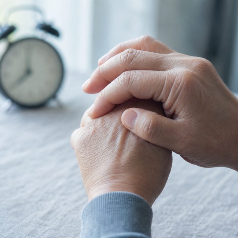 Dłonie rozmasowujące zesztywniałe palce dłoni o poranku, w chłodnym świetle